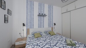 A bedroom with a bed, bedside tables, a wardrobe, and a wall with vertical stripes.