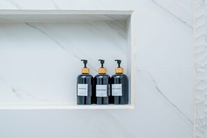 Un estante de baño con tres botellas de champú, acondicionador y gel de ducha.