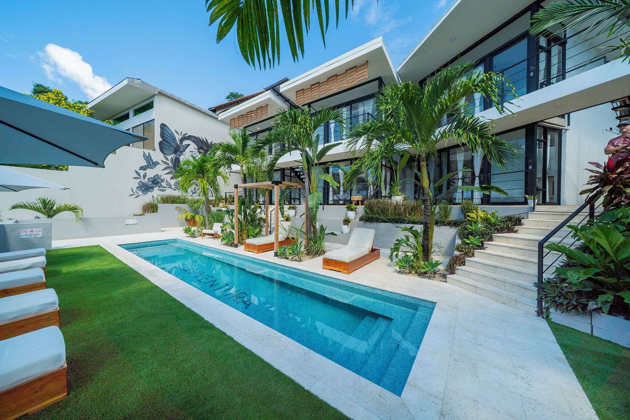 Une maison moderne dotée d’une piscine, d’un espace salon extérieur et d’une végétation luxuriante.