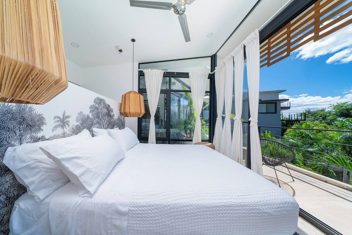 Un dormitorio moderno con una cama grande, un ventilador de techo y vistas al exterior.