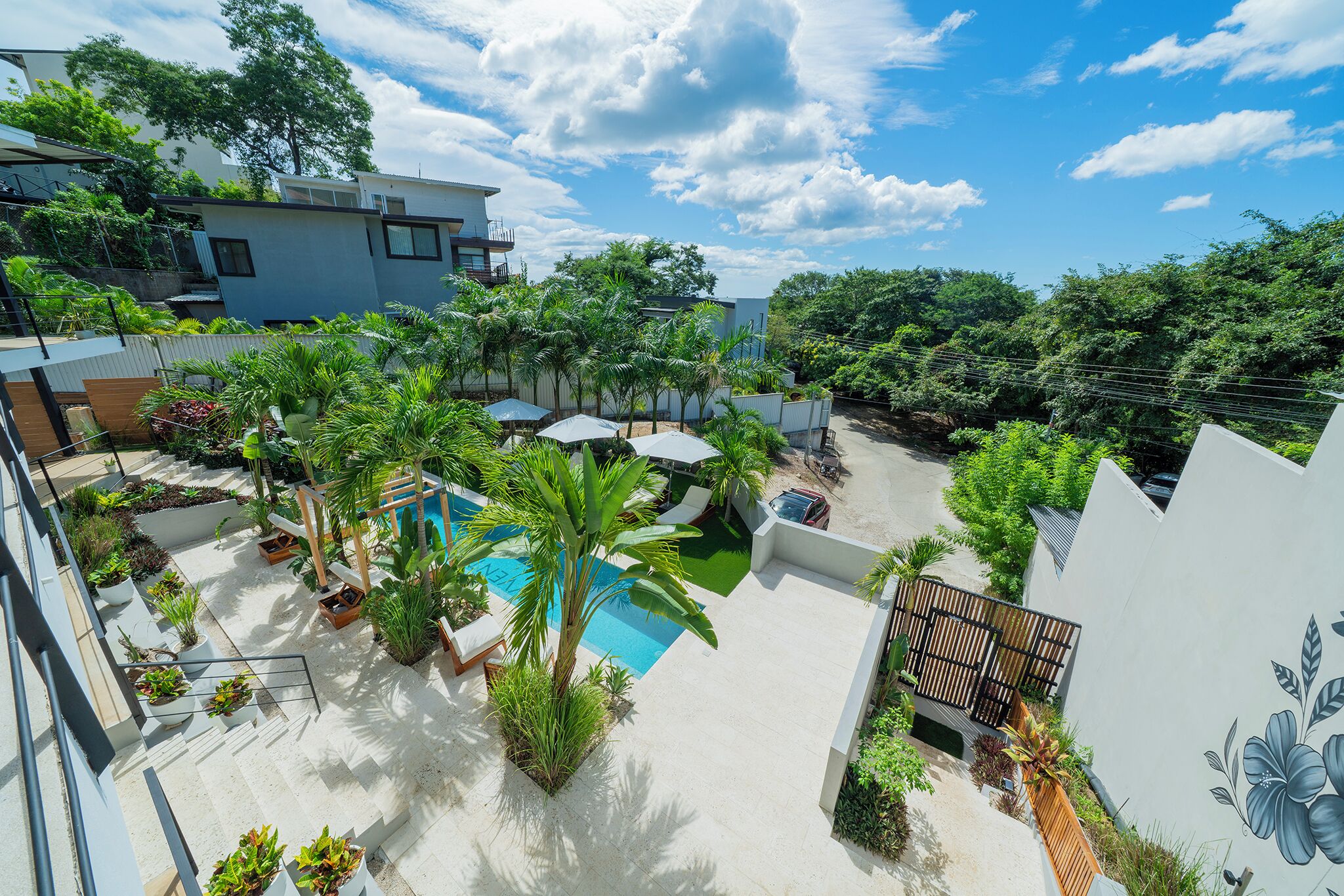 A rooftop garden with a swimming pool, lounge chairs, and potted plants.