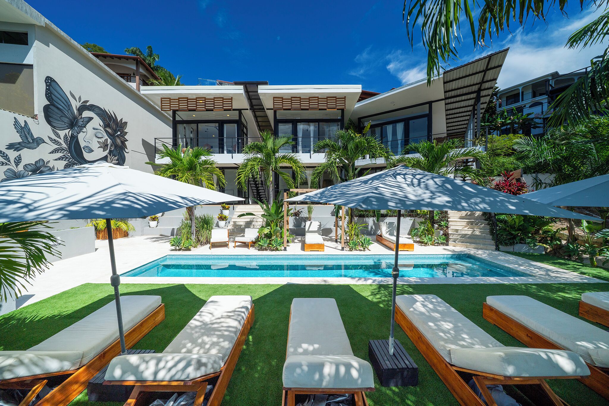 Una piscina al aire libre, sombrillas, sillones reclinables de piscina