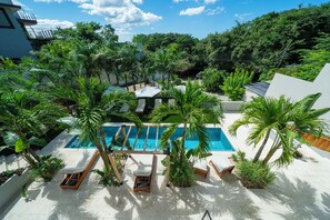 Un área de piscina con sillas de descanso y palmeras.