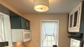 Una cucina compatta con fornello, lavello e frigorifero, caratterizzata da un pavimento decorato e una finestra con tende.