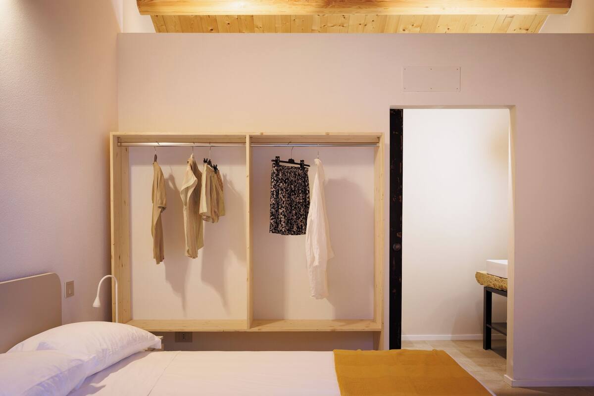 A room with a bed, a skylight, a wardrobe, and a small table.