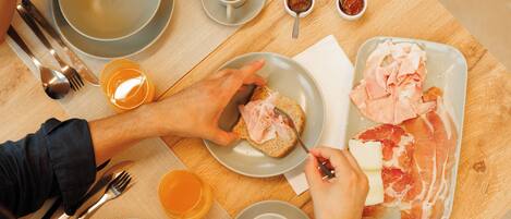 A breakfast setting with a plate of ham and cheese, a cup of coffee, and a bowl of soup.