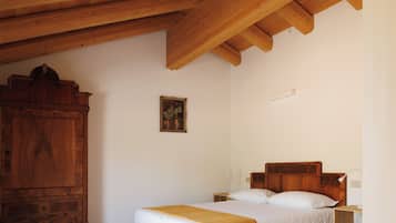 A bedroom with a wooden ceiling, a bed with white bedding, a wooden cabinet, and a small bedside table.