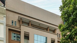 Un hotel con fachada moderna, varios balcones y una entrada de vidrio destacada.