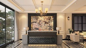 Zona de recepción con un gran mural, una araña y un área de estar con sofá y sillones.