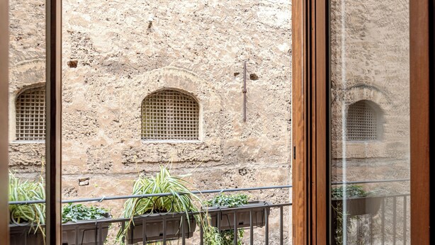 Ein Blick auf ein Steinhaus mit Bogenfenstern und einem Balkon mit Blumentöpfen.