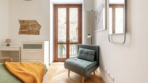 Ein Schlafzimmer mit Bett, Schreibtisch, Stuhl, Fenster und Tür.