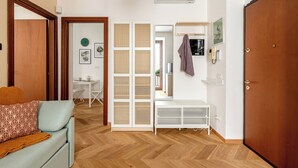 Ein Zimmer mit Holzboden, einer Couch, einem weißen Konsolentisch, einem Holzschrank und einem weißen Klimagerät.