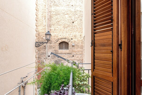 A narrow alleyway with a wooden door on the right, a metal lamp post, and a small window on a stone wall. - Casa Dolce Vita by Wonderful Italy (Palermo)