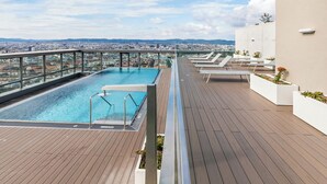 A rooftop pool with a city view, wooden deck, and lounge chairs. - Penthouse Apartment with Rooftop Pool (Vienna)