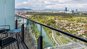 A balcony with a view of a river, cityscape, and greenery. - Penthouse Apartment with Rooftop Pool (Vienna)