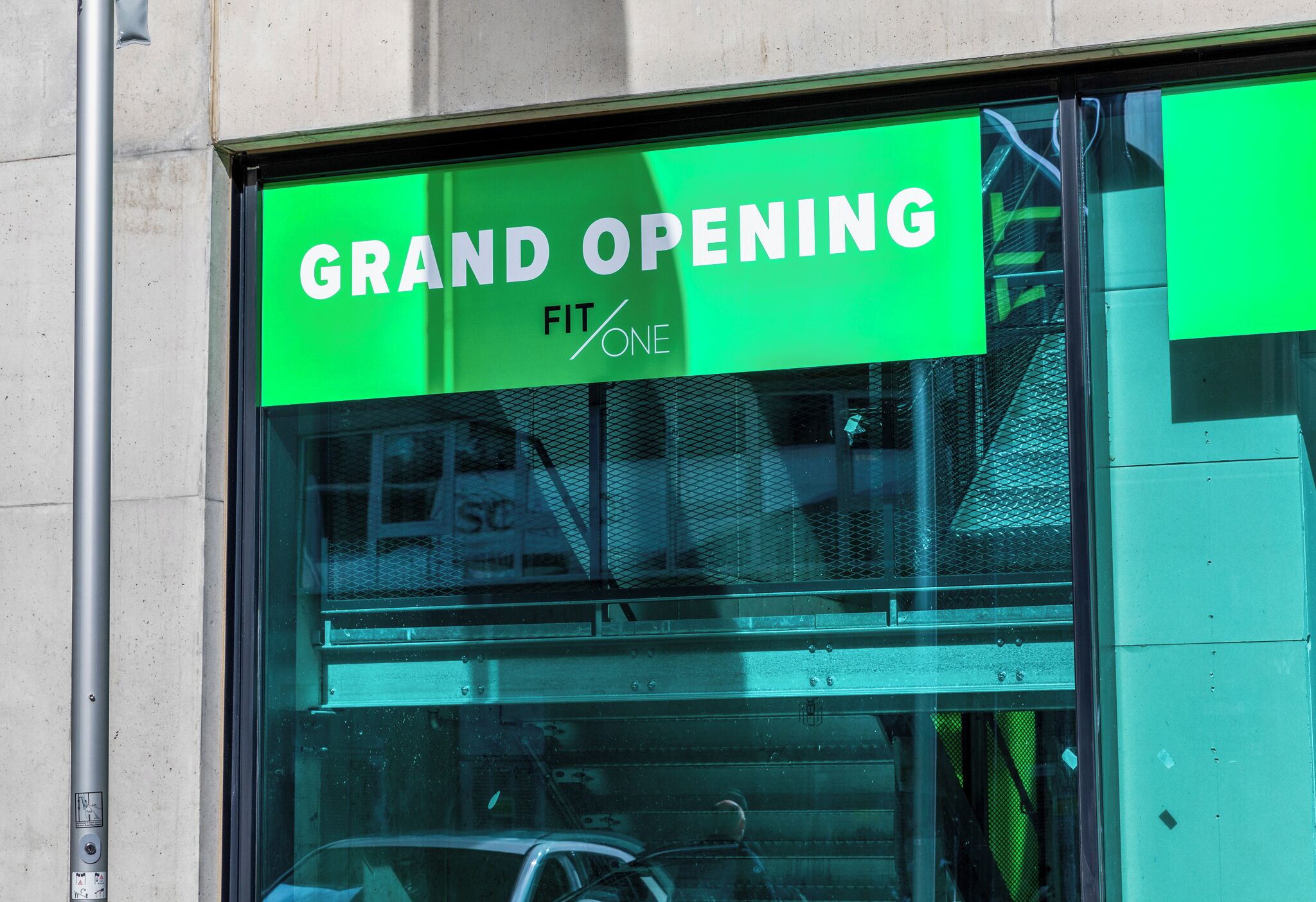 Letrero anuncia la gran inauguración de un gimnasio llamado FitOne.