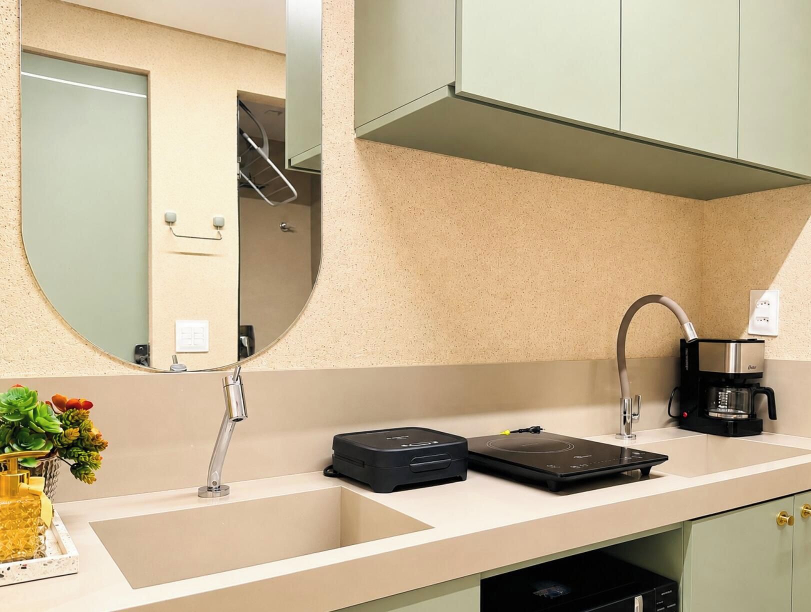 Una cucina moderna con lavello, macchina da caffè e frigorifero compatto.