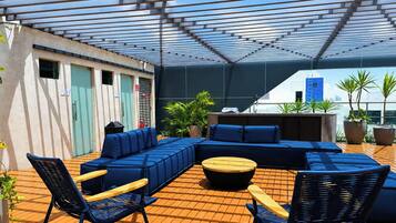 Un área de estar al aire libre con un sofá modular, sillas y una mesa redonda.