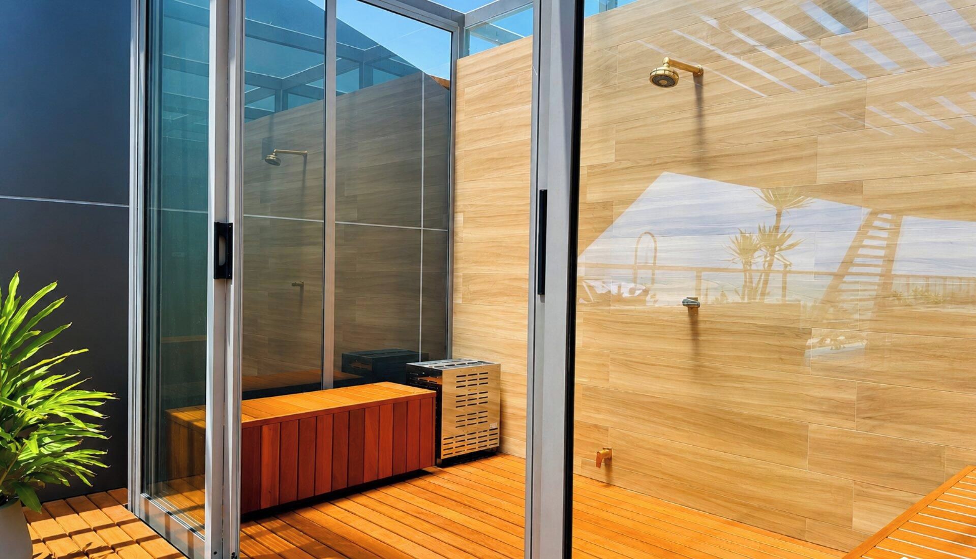Un bagno moderno con cabina doccia in vetro, pavimento in legno e una panca.