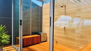 Ein modernes Badezimmer mit Duschkabine aus Glas, Holzboden und Sitzbank.