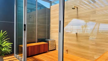 Un bagno moderno con cabina doccia in vetro, pavimento in legno e una panca.