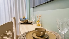 A dining table set with a cup, saucer, and glassware, with a decorative vase and reed diffuser in the background. - Setai Aquamaris - LikeHome Hospedagens (João Pessoa)