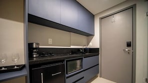 A modern kitchen with dark cabinetry, a microwave, and a coffee maker. - Setai Aquamaris - LikeHome Hospedagens (João Pessoa)
