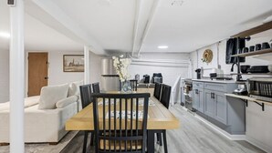 Een moderne keuken met grijze kastjes, een houten eettafel en een zwarte stoel.