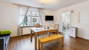 Una habitación moderna y bien iluminada con una mesa de comedor de madera, un banco y un televisor de pantalla plana montado en la pared.
