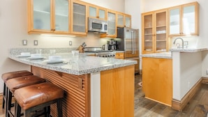 A kitchen with wooden cabinets, a stainless steel refrigerator, a microwave, a stove, and a coffee maker. - Bright Spacious Condo with Spa Access 638 (Mammoth lakes)