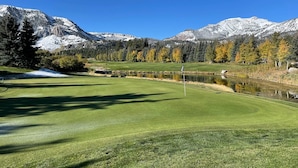 A golf course with a pond, trees, and mountains in the background. - Bright Spacious Condo with Spa Access 638 (Mammoth lakes)