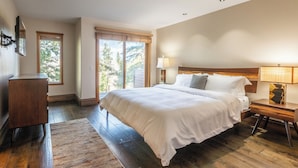 A bedroom with a large bed, a nightstand, a lamp, a dresser, and a window with blinds. - Bright Spacious Condo with Spa Access 638 (Mammoth lakes)