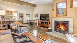 A spacious living room with a fireplace, a television, and a dining area. - Bright Spacious Condo with Spa Access 638 (Mammoth lakes)