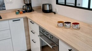 Een moderne keuken met witte kasten, een roestvrijstalen fornuis en een koffiezetapparaat.