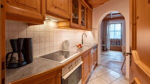 A kitchen with wooden cabinets, a countertop, a coffee maker, a sink, and an oven. - Apartment "Hans" with Mountain View, Balcony and Wi-Fi (Fügen)