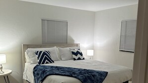A bedroom with a bed, two bedside tables, a window with blinds, and a door. - Marvelous 3-bedroom house located on a horse farm in Ocala minutes from WEC (Ocala)