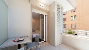 A small balcony with a table, chair, and a door leading to a bedroom. - Chessa's Rooms (Rome)