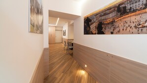 A hallway with wooden flooring, a dining area with chairs, and a large cityscape painting on the wall. - Chessa's Rooms (Rome)