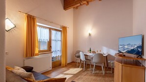 A cozy room with a sofa, dining table, chairs, a TV, and a window with curtains. - Apartment 'Lisa' with Mountain View, Balcony and Wi-Fi (Fügen)