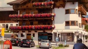 A wooden building with balconies adorned with colorful flowers, a sign for 'Ost Gemuse,' and a parking sign. - Apartment 'Lisa' with Mountain View, Balcony and Wi-Fi (Fügen)
