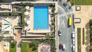 Ett flygbildsfoto av ett hotell med en stor swimmingpool, flera sällskapsytor och en parkeringsplats med ett antal bilar.