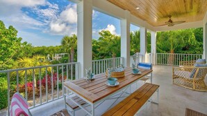 A covered outdoor patio with wooden furniture, white railings, and lush greenery in the background. - P01 - New 3 bed, 3 bath with private pool (Marathon)