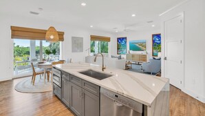 A modern kitchen with a central island, a dishwasher, and a dining area with a round table and chairs. - P01 - New 3 bed, 3 bath with private pool (Marathon)