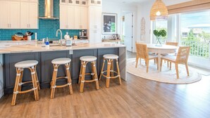 A modern kitchen with a central island, bar stools, and a dining area with wicker chairs and a table. - P01 - New 3 bed, 3 bath with private pool (Marathon)