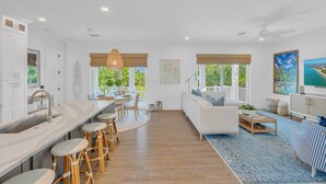 A spacious kitchen with a dining area, a living room with a sofa and coffee table, and large windows with a view of greenery. - P01 - New 3 bed, 3 bath with private pool (Marathon)
