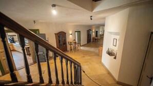 A spacious hallway with a wooden staircase, a dining area, and a kitchen visible in the background. - Landhotel Alte Zollstation (Pittenhart)