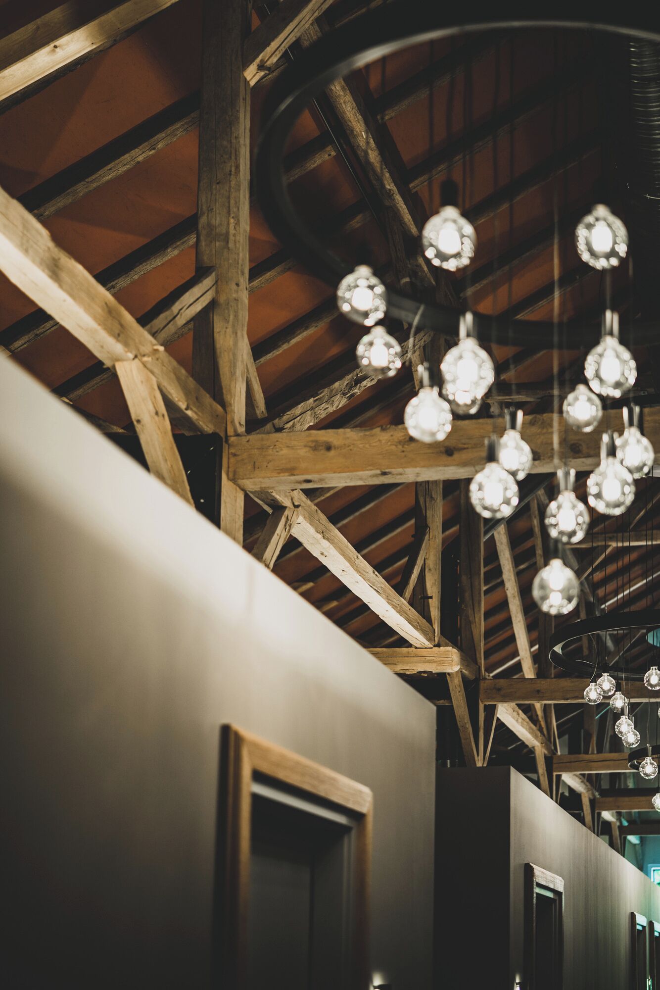A rustic interior with exposed wooden beams and hanging spherical light fixtures.