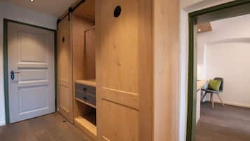 A room with a wooden wardrobe, a white door, and a desk with a chair.
