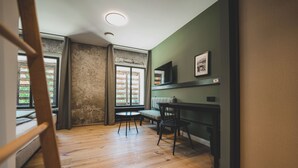 A room with a wooden floor, a dining table with chairs, a window with curtains, and a framed picture on the wall. - Landhotel Alte Zollstation (Pittenhart)