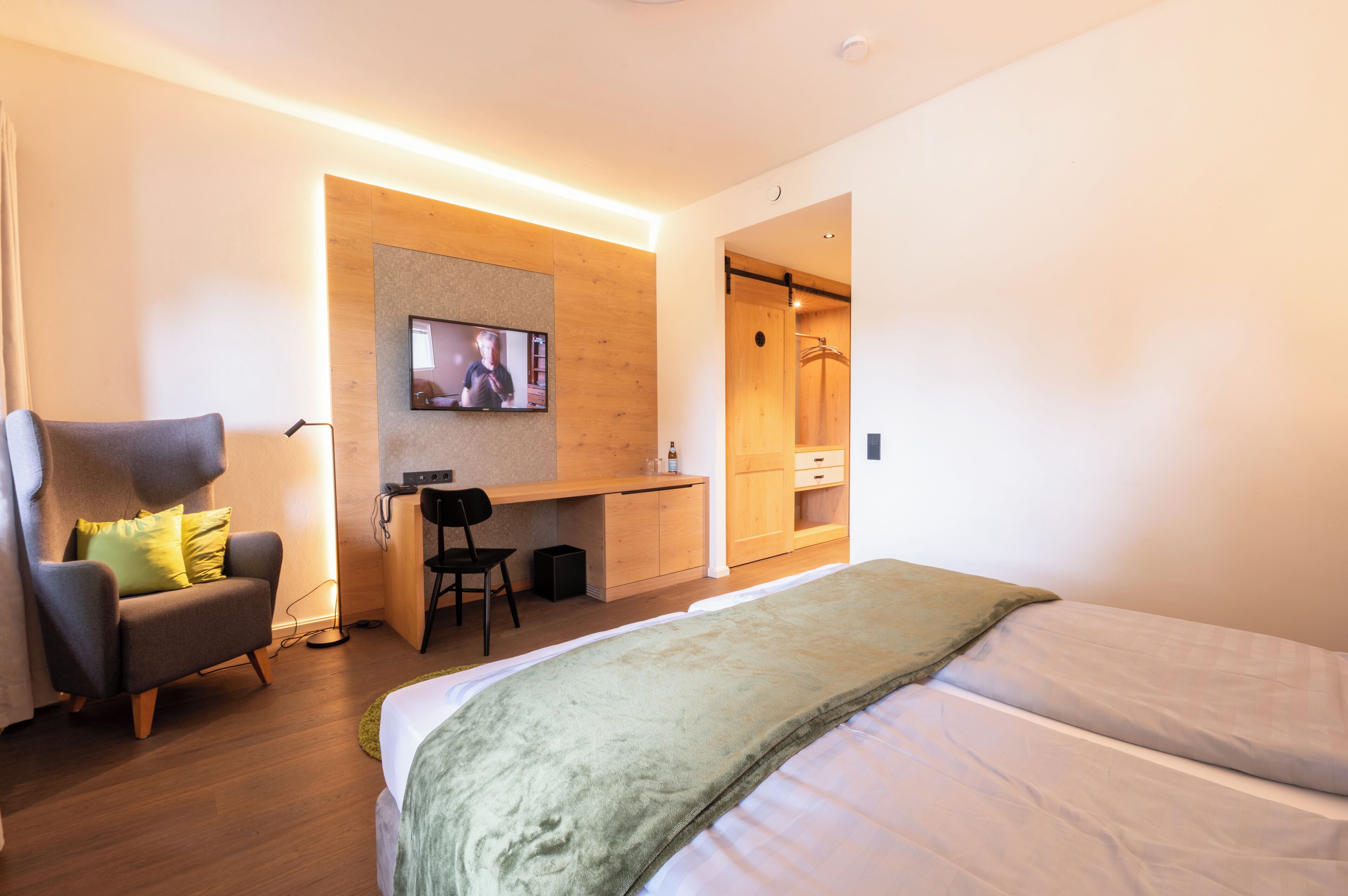Ein modernes Hotelzimmer mit Bett, Schreibtisch, Stuhl und Fernseher.